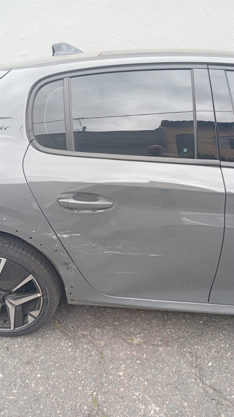 Peugeot 208 com riscos e amassado na porta traseira
